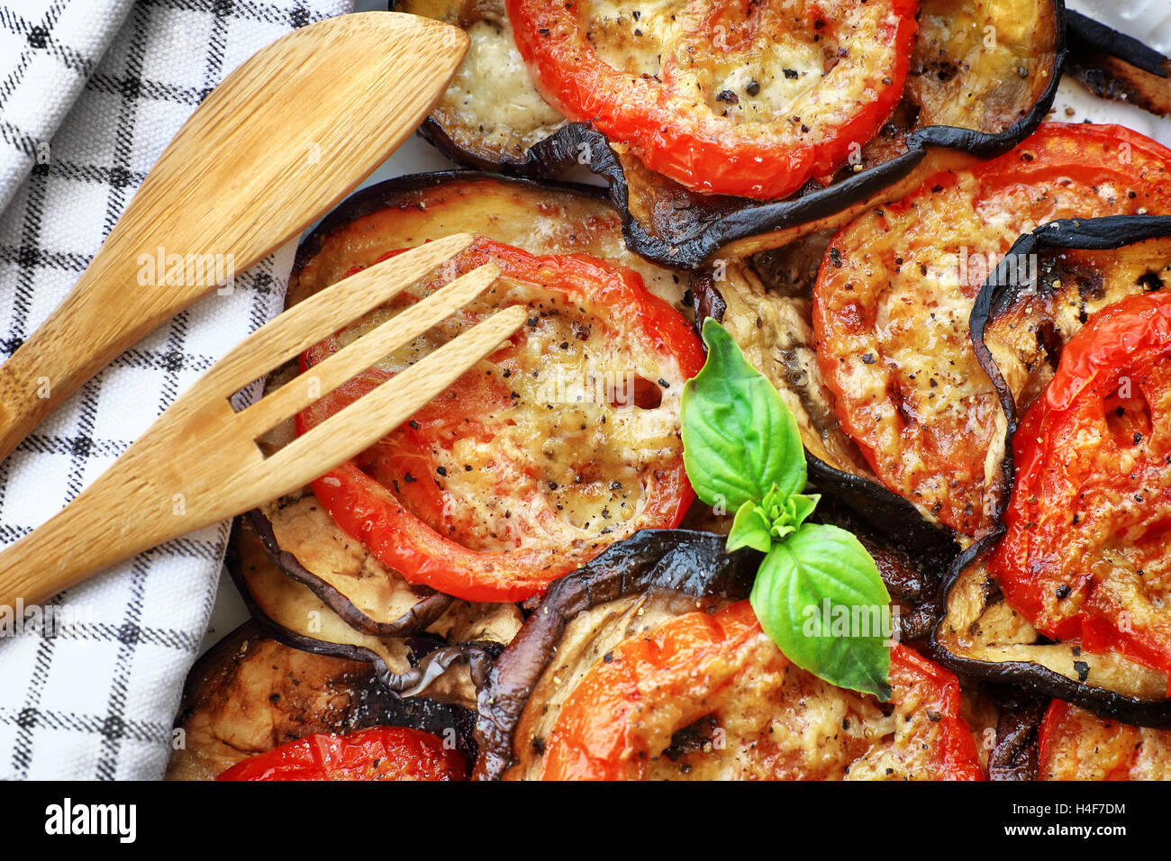 Köstliche vegetarische Pizza Hintergrund, gebratene Auberginen mit Tomaten und Basilikum auf dem Teller auf dem Holztisch Stockfoto