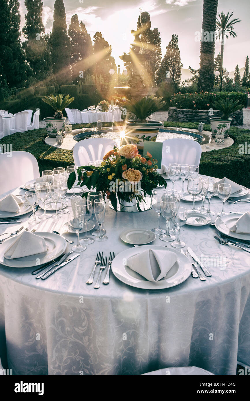 Gartentisch-Einstellung bei Hochzeitsfeier unter Sonnenuntergang Sonnenstrahlen. Jahrgang gefiltert Stockfoto