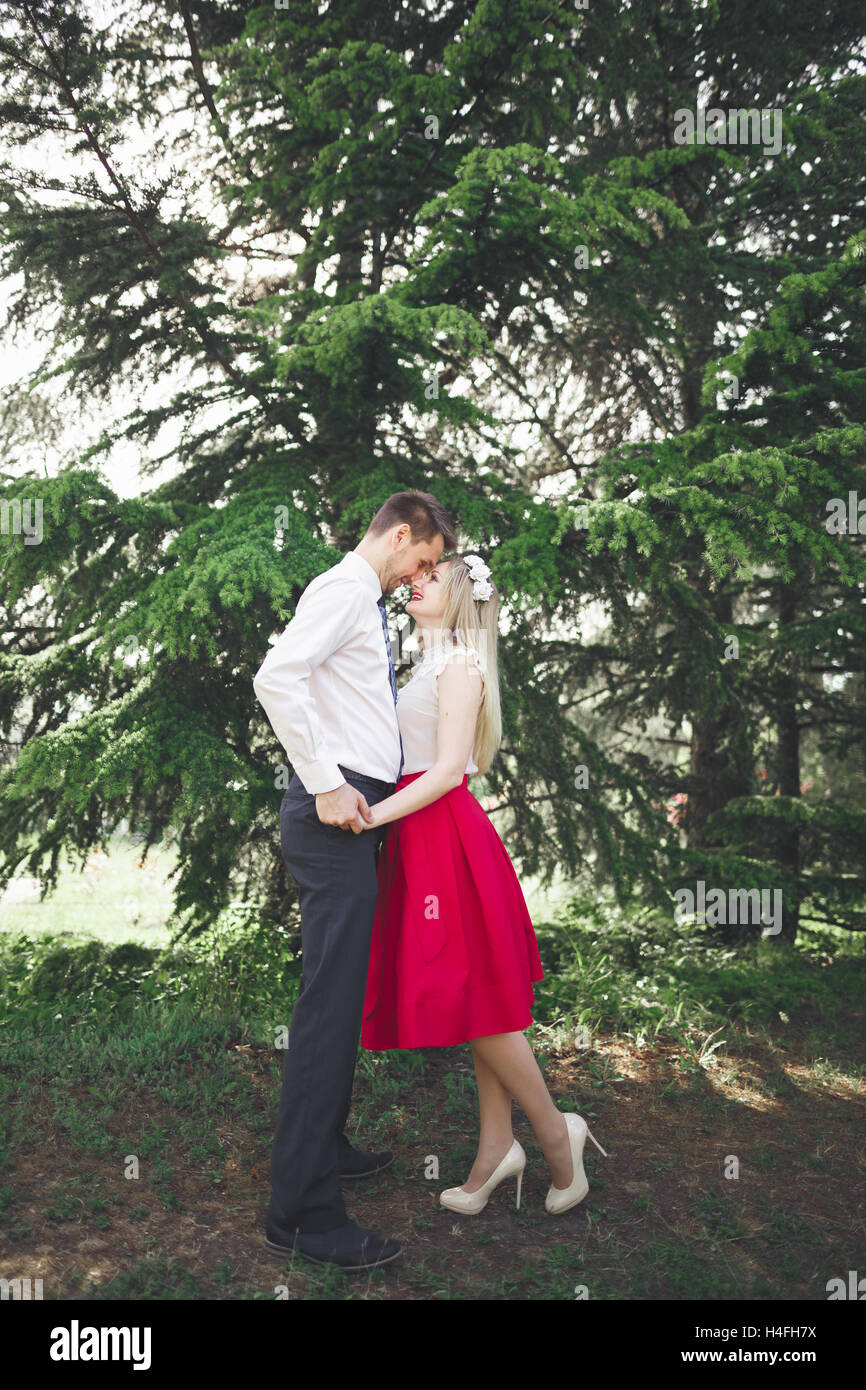 Junge schöne Paar küssen und umarmen in der Nähe von Bäumen mit Blüte im Sommerpark Stockfoto