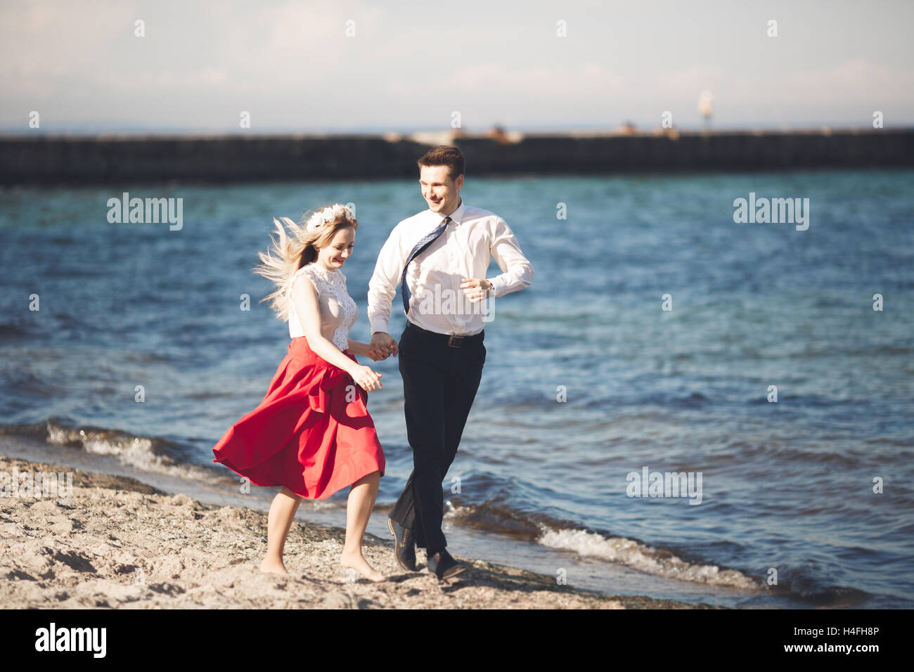 Junge glückliche Paar zu Fuß am Strand lächelnd Holding umeinander. Liebesgeschichte Stockfoto