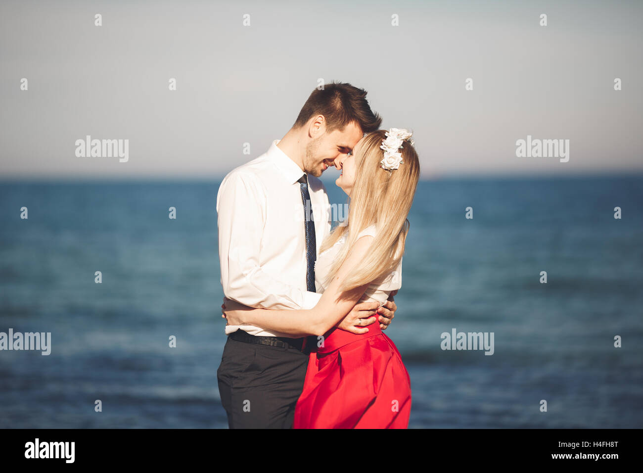 Junge glückliche Paar zu Fuß am Strand lächelnd Holding umeinander. Liebesgeschichte Stockfoto