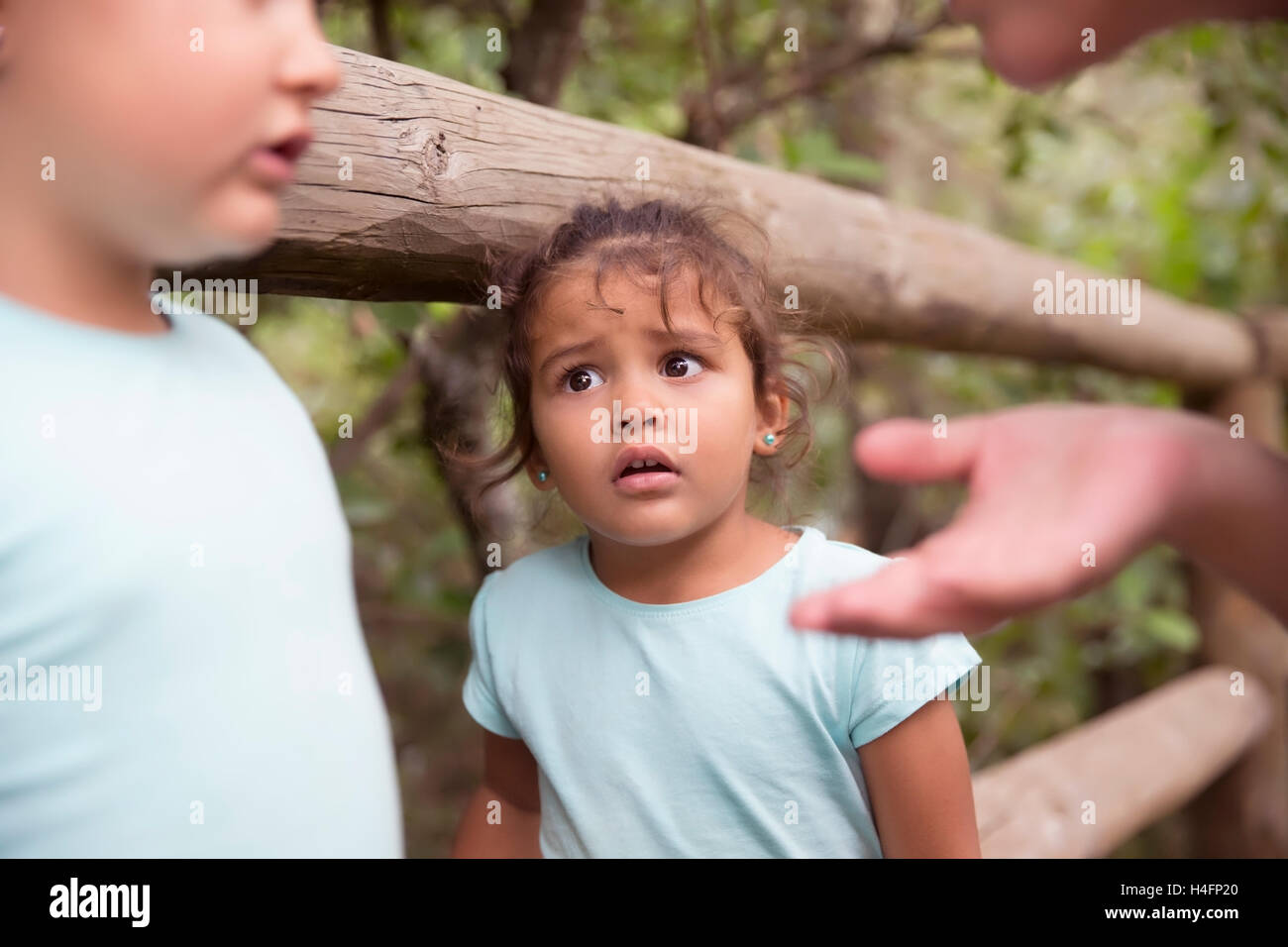 Porträt von unschuldigen niedliche kleine Mädchen sah ihre Schwester und Mutter mit Augen voller Angst im Park gegen Bäume Stockfoto