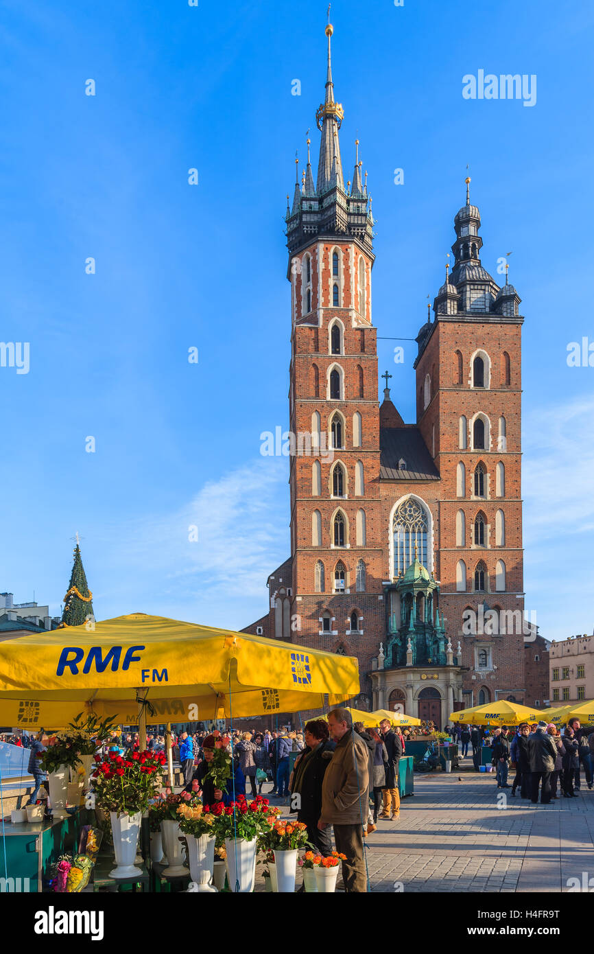 Krakau, Polen - 13. Dezember 2014: Touristen von Blumen am Main Markt Platz von Krakau mit Marienkirche im Hintergrund. Jedes Jahr findet ein Weihnachtsmarkt in der Altstadt von Krakau, Polen. Stockfoto