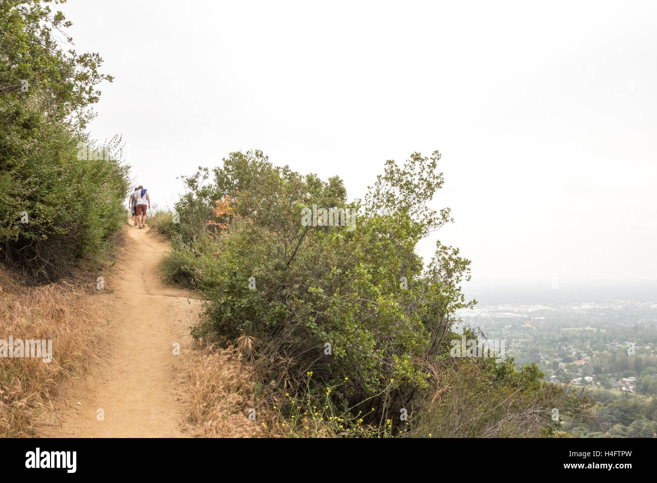 Wanderer zu Fuß den Weg hinauf auf Bailey Canyon außerhalb von Los Angeles mit Sierra Madre in der Ferne Stockfoto