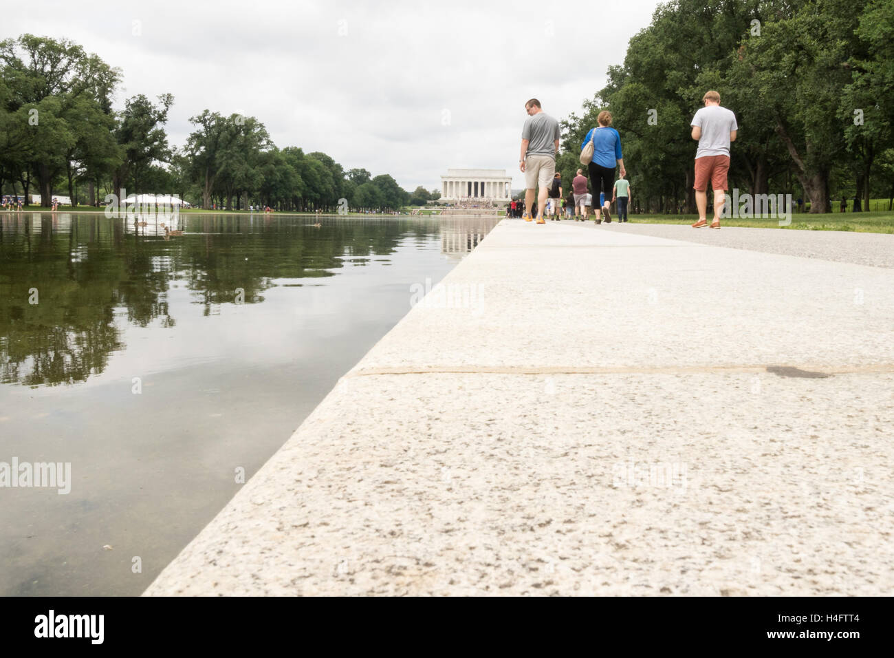 Ansicht des Lincoln Memorial aus dem reflektierenden Pool mit Touristen zu Fuß entlang des Ufers Stockfoto