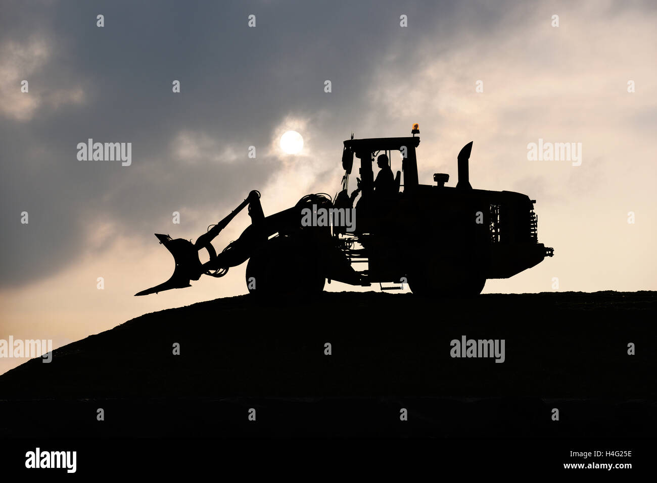 Schaufel, Silhouette, Radlader Rollen Silage Haufen auf einem Bauernhof in der Dämmerung mit Vollmond. Stockfoto