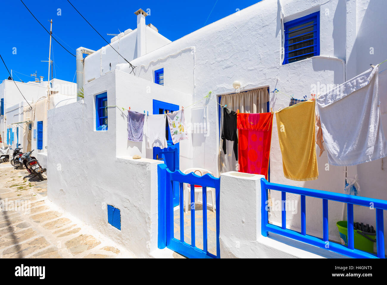 Die Stadt MYKONOS, Griechenland - 15. Mai 2016: Klamotten vor einem Haus mit blauen Türen und Fenster in weiß getünchten Straße im Myko Stockfoto