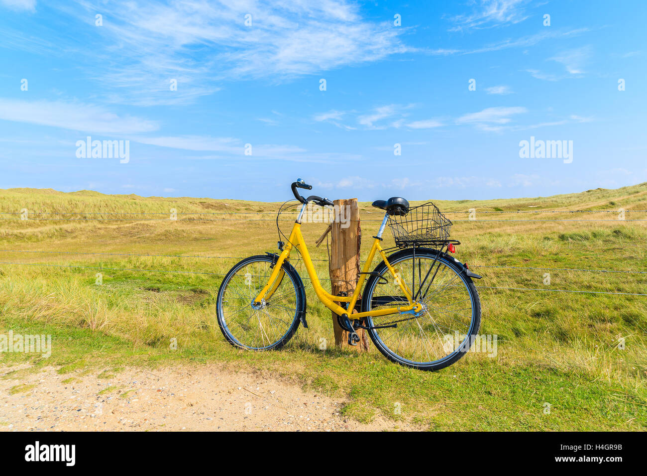 SYLT, Deutschland - Sep 6, 2016: gelb Fahrrad gegen ein Feld Zaun in der Landschaft Landschaft der Insel Sylt Leuchtturm Ellenbogen in der Nähe geparkt. Stockfoto