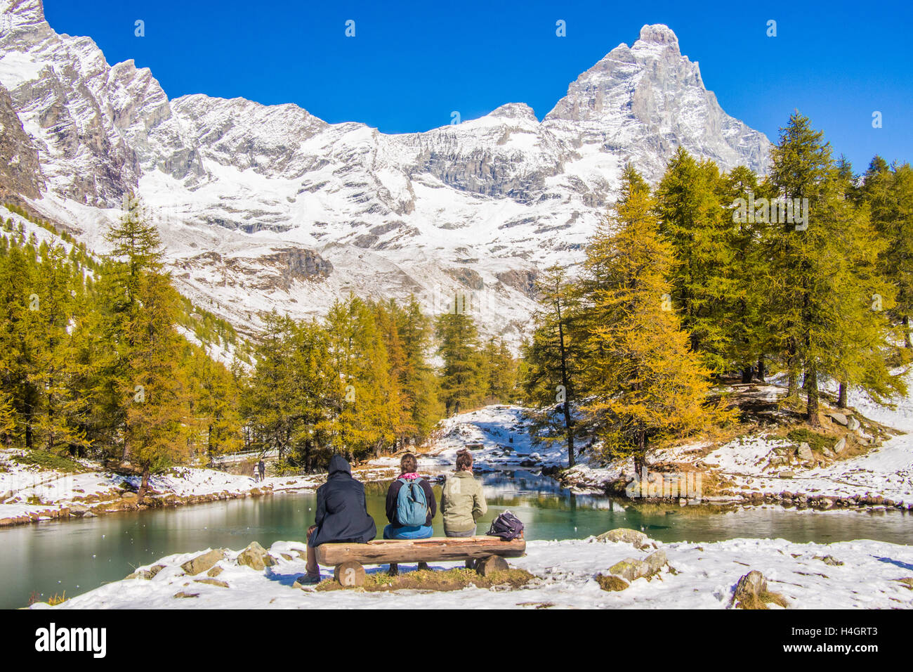 Lago Blu (Blauer See) mit dem Cervino Berg (in der Schweiz auch bekannt als "Matterhorn"), Aostatal, Italien. Freunde sitzen auf einer Bank. Stockfoto