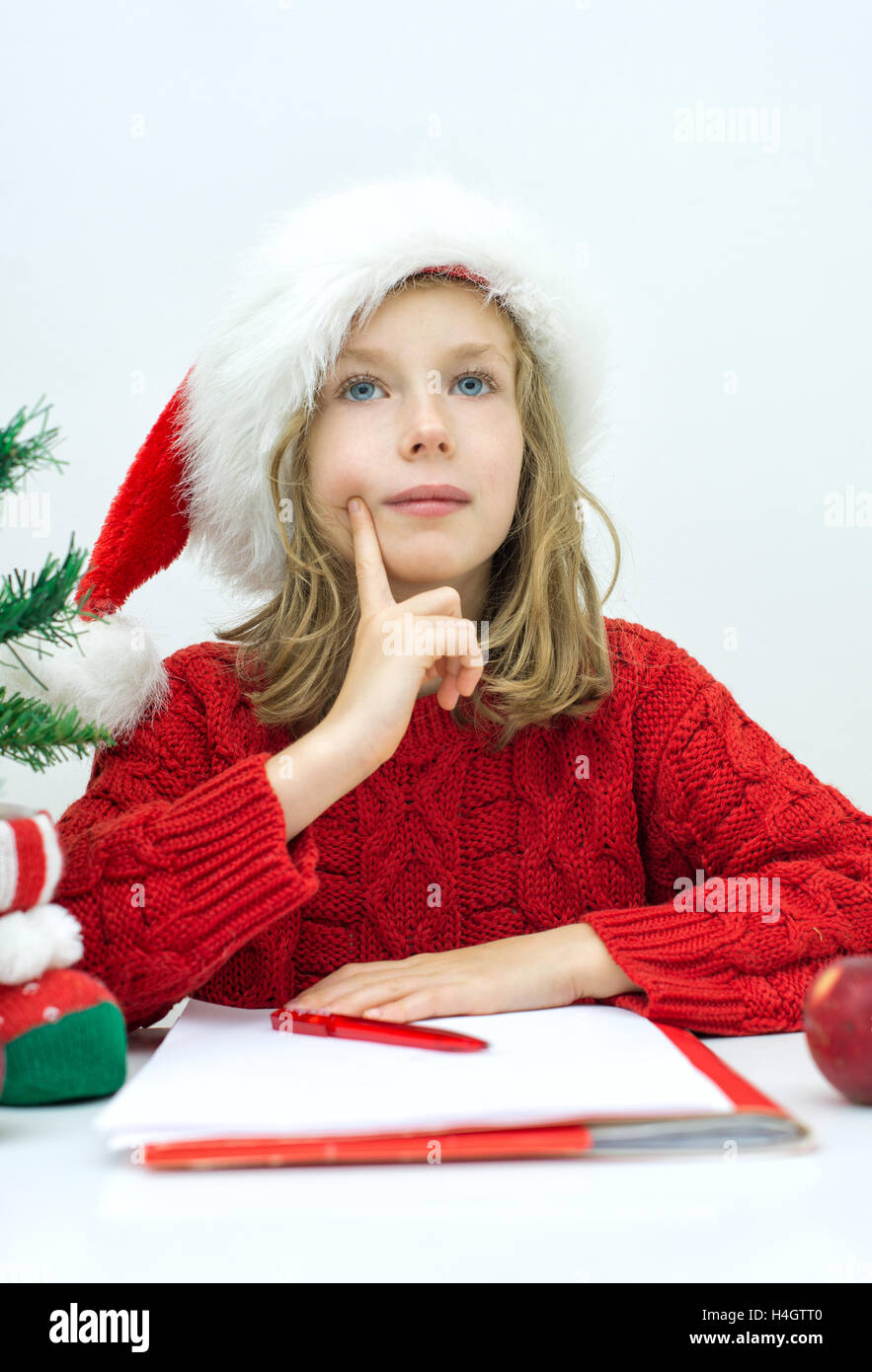 Kleines Mädchen im roten Hut einen Brief an den Weihnachtsmann schreiben. Stockfoto