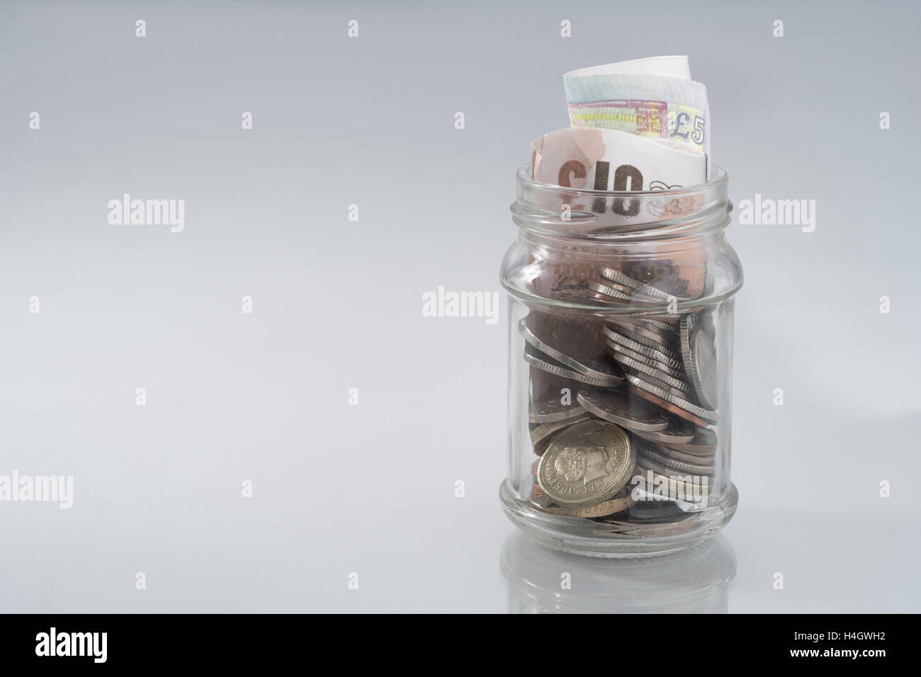 Bild von Jam jar mit Loose Change & Geld. Metapher Lebenshaltungskosten, verfügbares Einkommen, regnerischer Tag sparen / Geld sparen Konzept, speichern Topf, Armut. Stockfoto