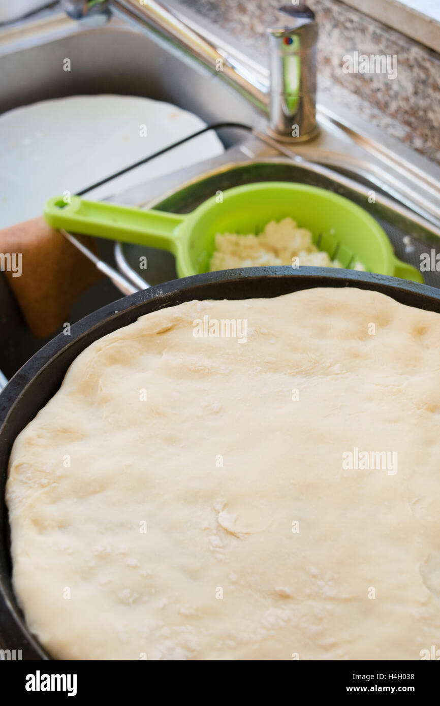 hausgemachten Teig der Pizza auf einem Backblech ausbreiten Stockfoto