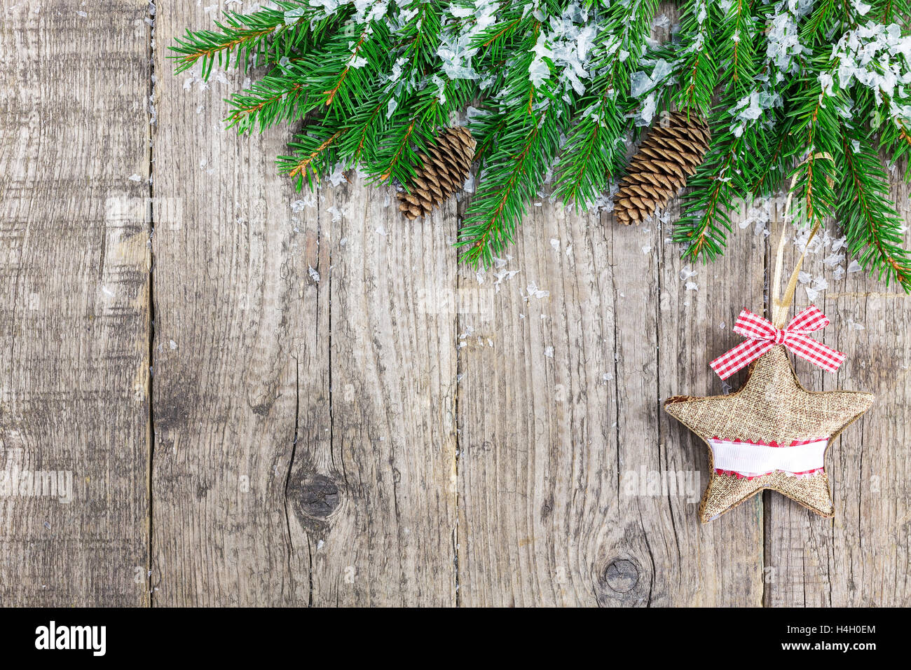 Weihnachten Tannenbaum bedeckt mit Schnee und festliche Stern mit roter Schleife auf Holzplatte Stockfoto