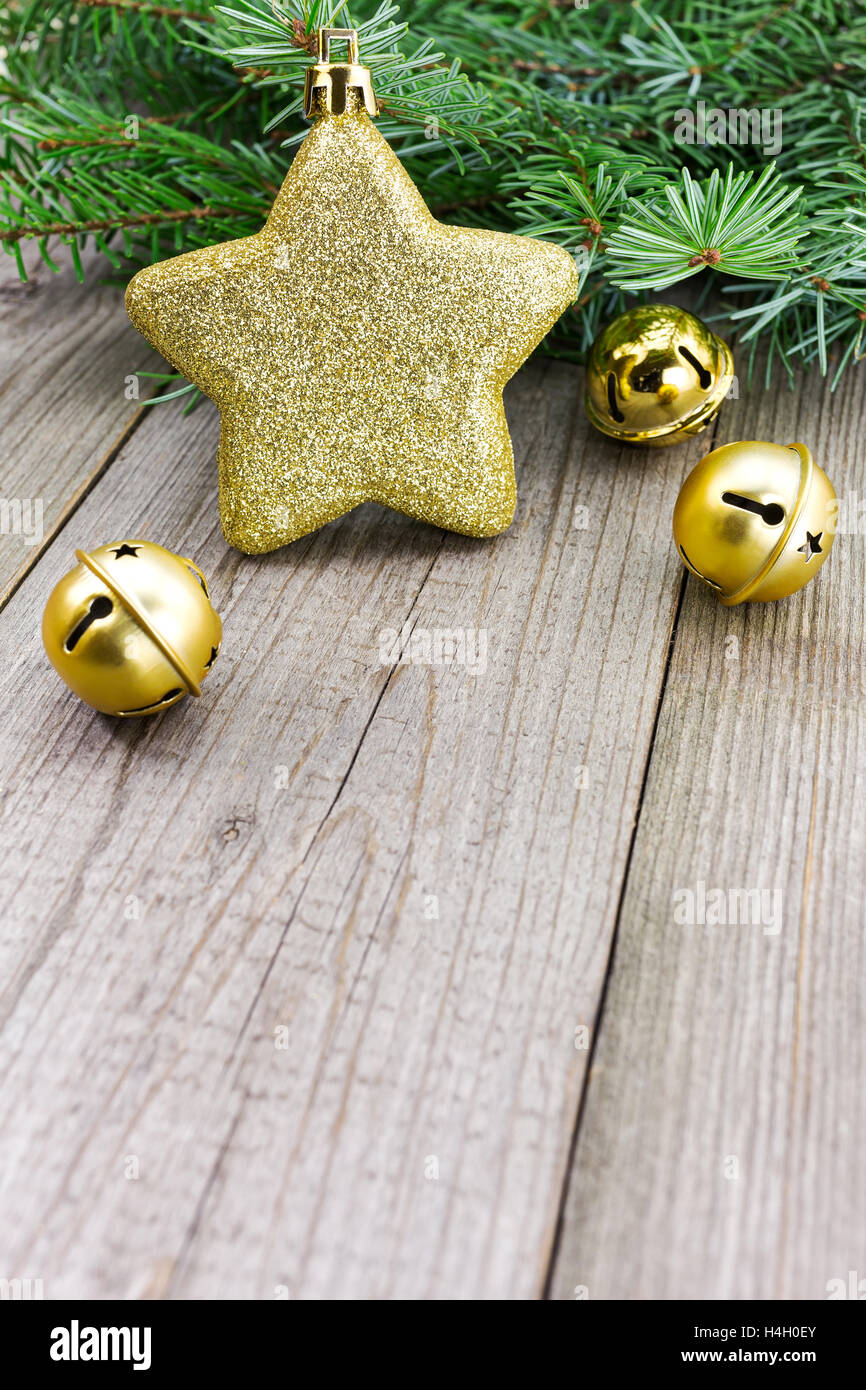 Goldener Stern mit Christmas Jingle Bells und Tanne Zweig auf verwitterten Holzbrett Stockfoto