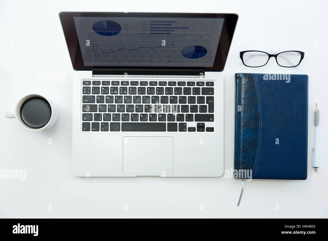 Weißer Schreibtisch mit Brille, Laptop, Kaffee und notebook Stockfoto