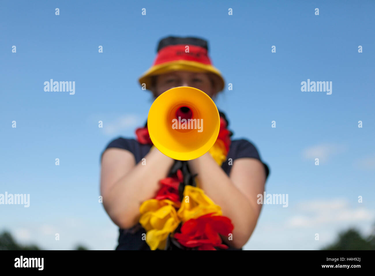 Junge Frau Blasen in einem Vuvuzela, schwarz rot gold, FIFA WM 2010 Stockfoto