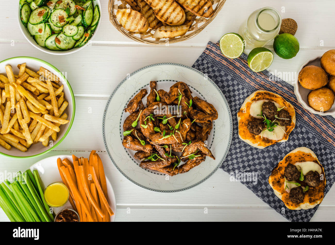 Hähnchenflügel, Gurkensalat, Pommes frites, Gemüse, Pizza, Donuts, Limettensaft, Dip und Toast. Stockfoto