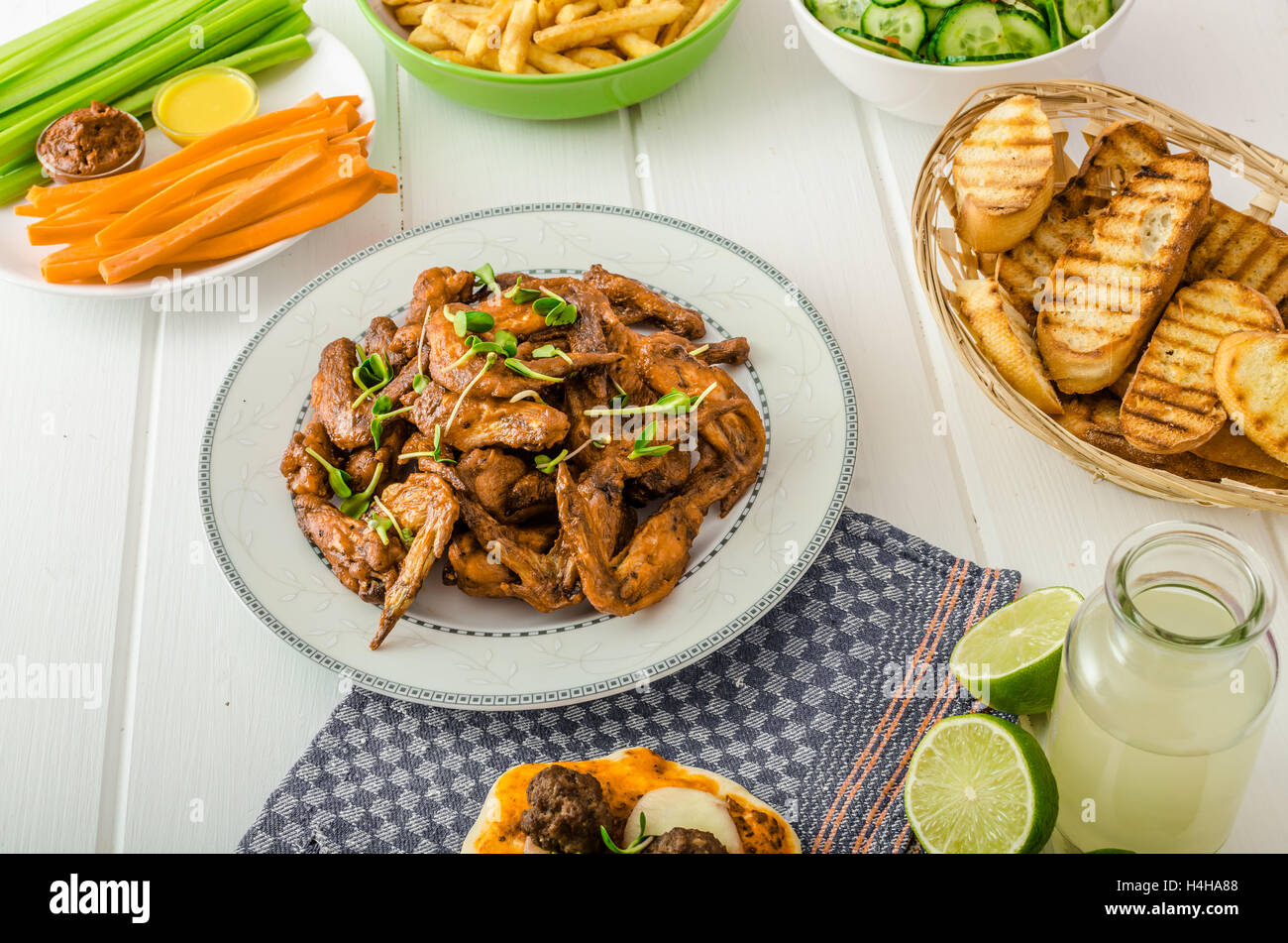 Hähnchenflügel, Gurkensalat, Pommes frites, Gemüse, Pizza, Donuts, Limettensaft, Dip und Toast. Stockfoto