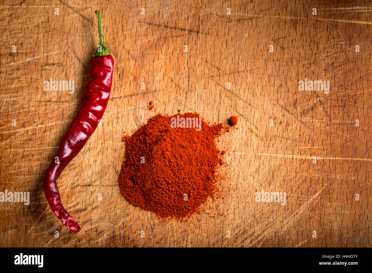 Rote heiße Paprika Pulver Heap und eine getrocknete Chili auf hölzernen Hintergrund Stockfoto
