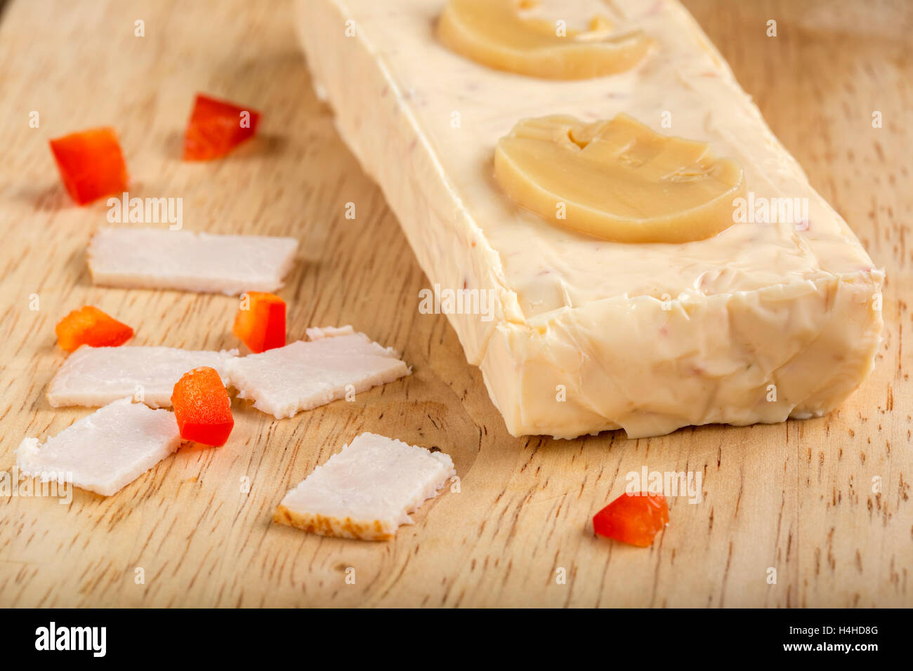 Block von Schmelzkäse mit Schinken, Paprika und Champignons in hölzernen Hintergrund Stockfoto