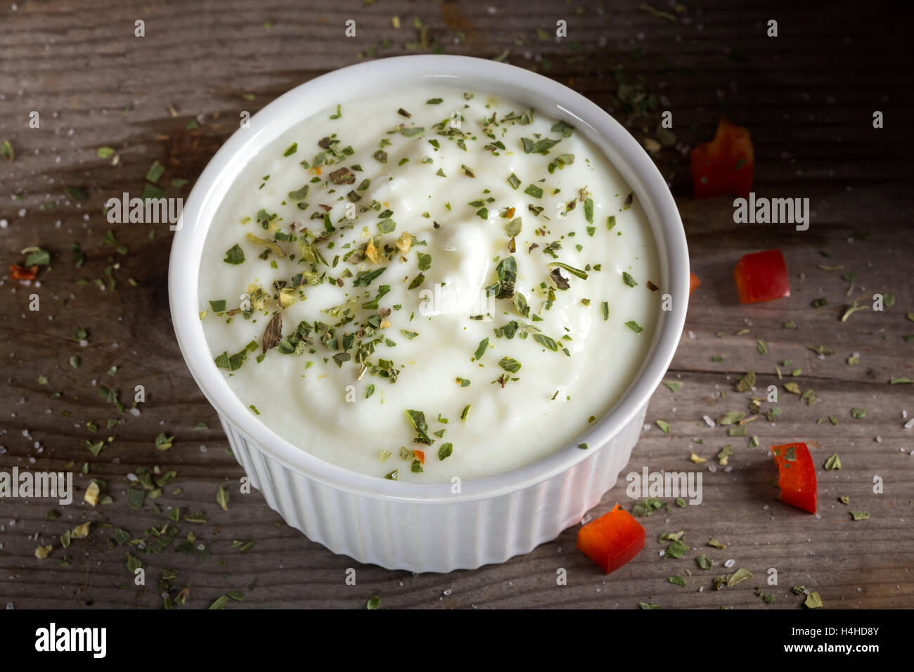 Sauce aus Joghurt und Kräutern in eine weiße Keramikschale auf einem Holztisch Stockfoto