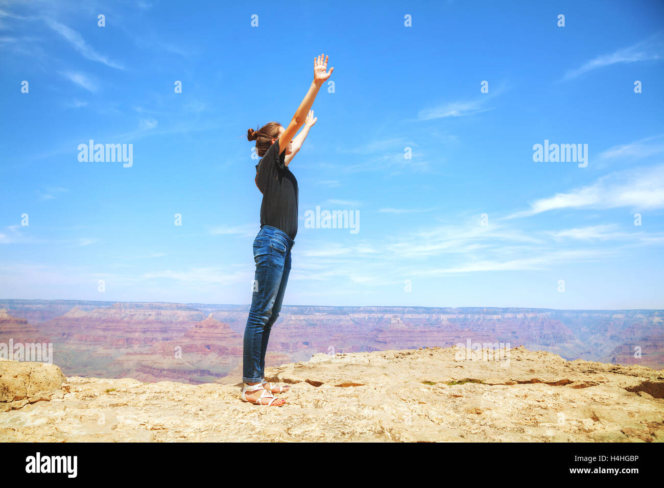 Junge Dame mit erhobenen Händen am Rand des Grand Canyon rim Stockfoto