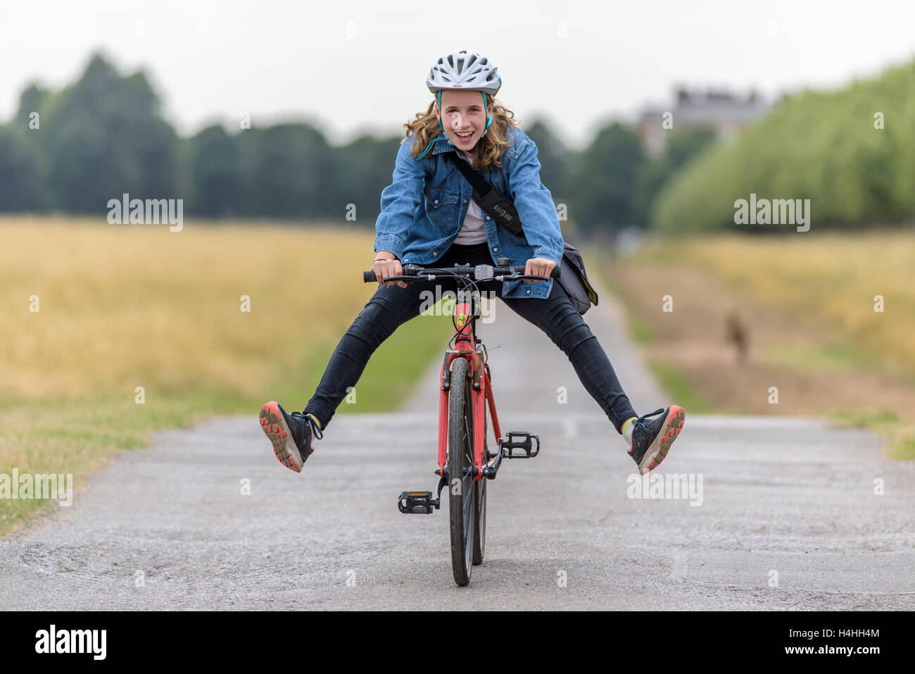 Ein Mädchen auf einem Fahrrad mit ihren Beinen von den Pedalen, die das Tragen eines Helms beim Radfahren Stockfoto