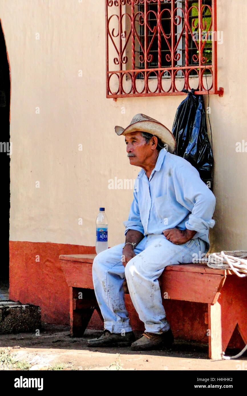 La Maquina, Guatemala – 16. Juni 2011: Guatemala Cowboy stützt sich auf eine kirchliche Bank in La Maquina, Guatemala. Nur zur redaktionellen Verwendung. Stockfoto