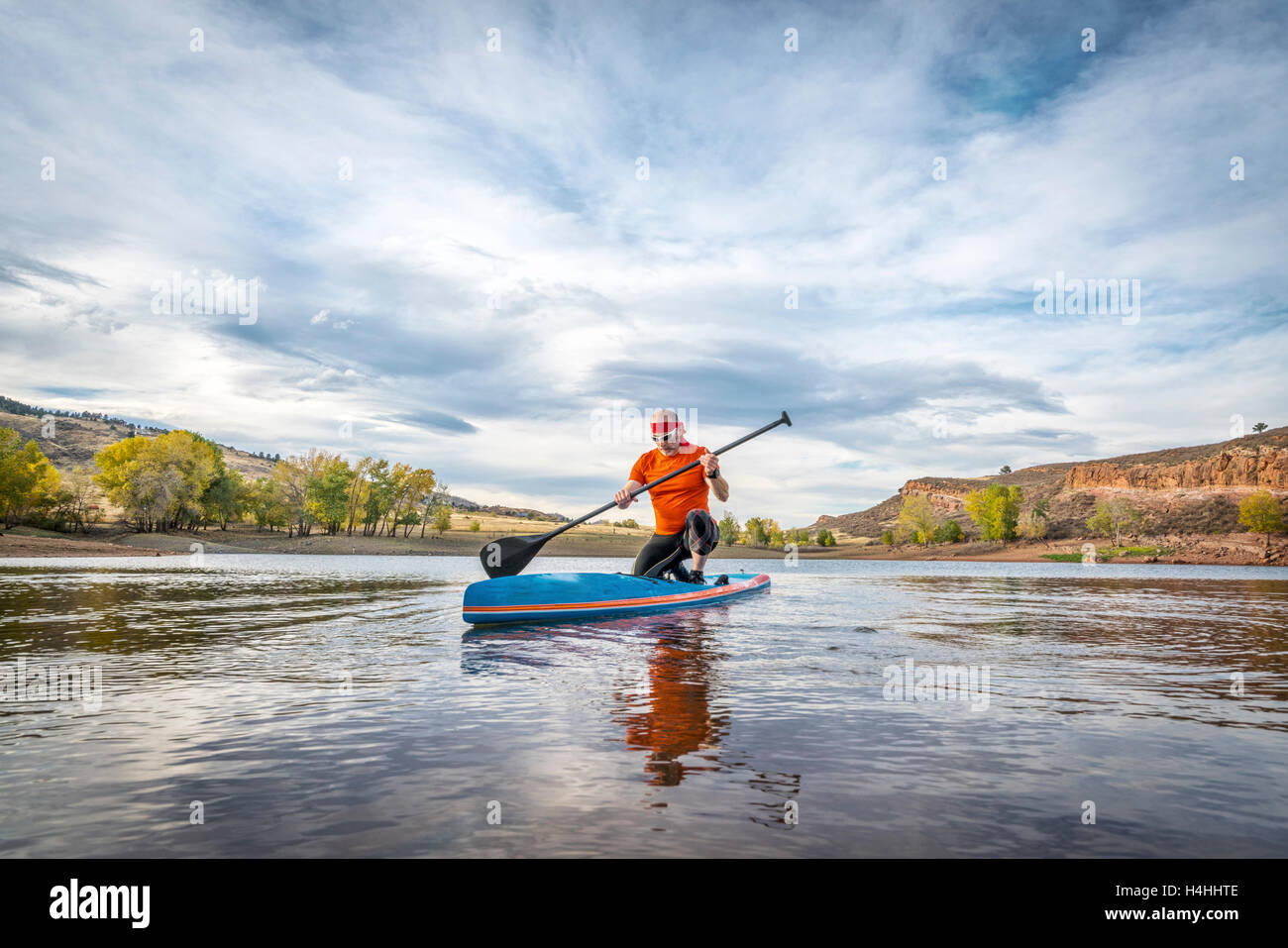 Ein Moment der Besinnung - ein senior männlich auf Stand up Paddleboard an einem ruhigen Bergsee Stockfoto