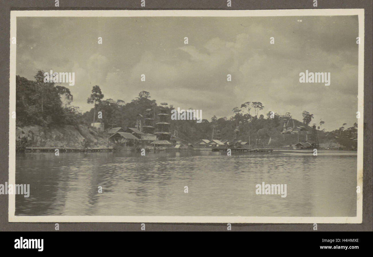 Bank von einem Dorf mit Bohrtürme und Gebäuden gesehen aus dem Wasser, Anonymous, Niederländisch-Indien, Indonesien Stockfoto