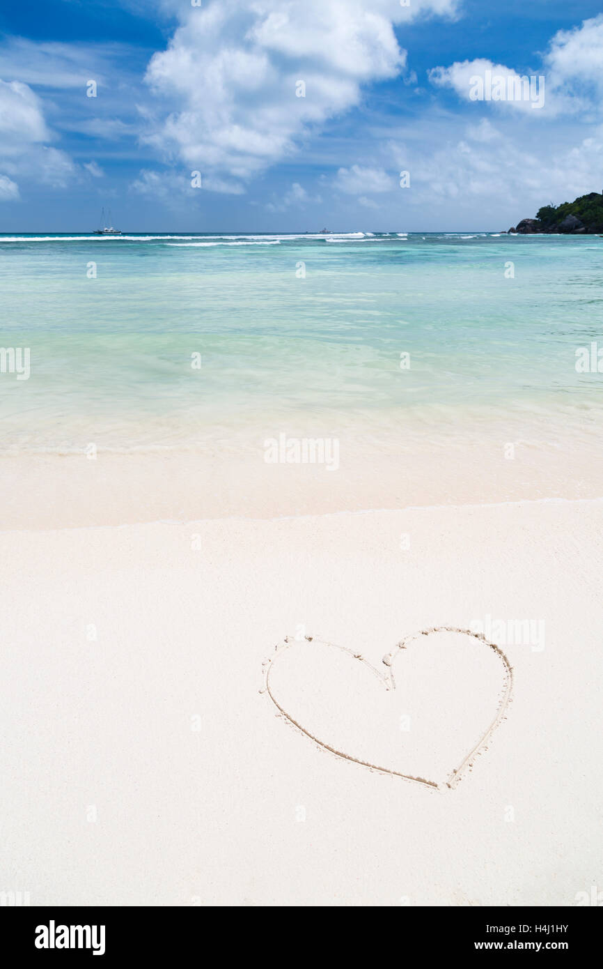 Herzform im Sand von einem sauberen weißen Strand mit türkisblauem Wasser Stockfoto