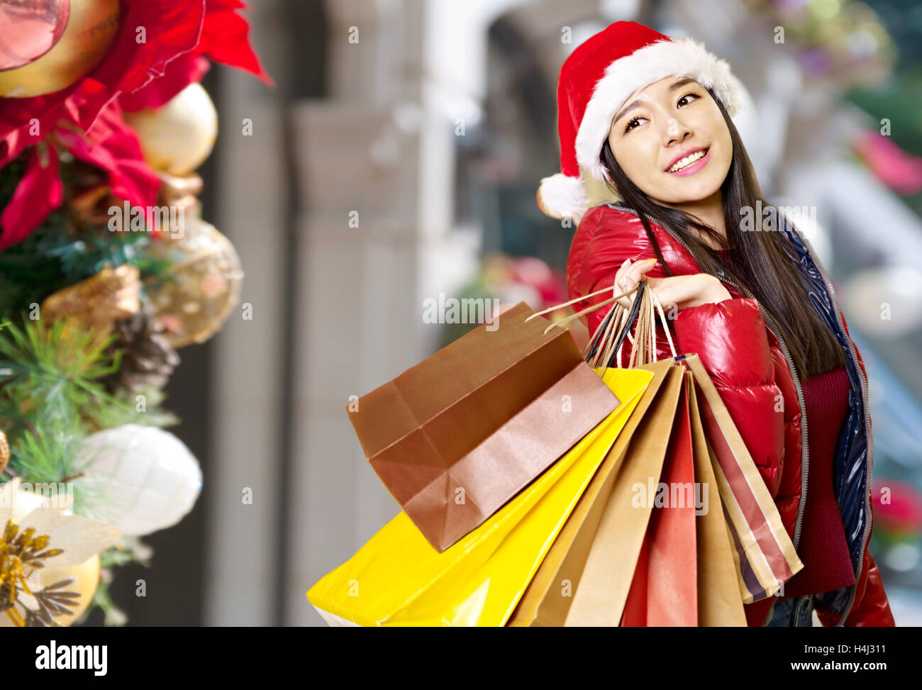 junge Asiatin Tragetaschen Papier auf Schulter beim Weihnachts-shopping, glücklich und lächelnd. Stockfoto