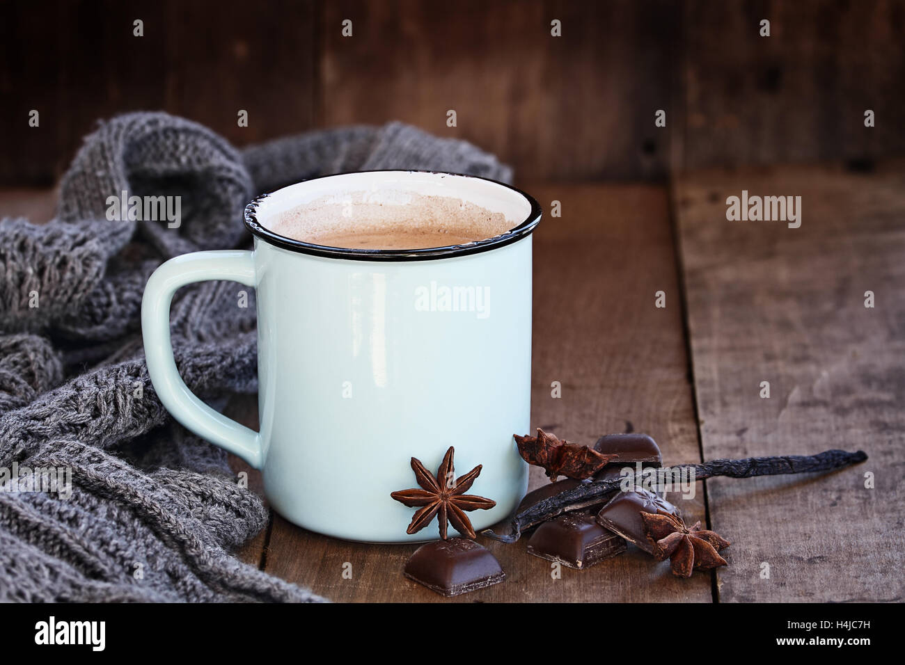Emaille Tasse heißen Kakao oder Kaffee zu Weihnachten mit Schokoriegeln, Vanilleschote, Gewürze und grauen Schal. Stockfoto