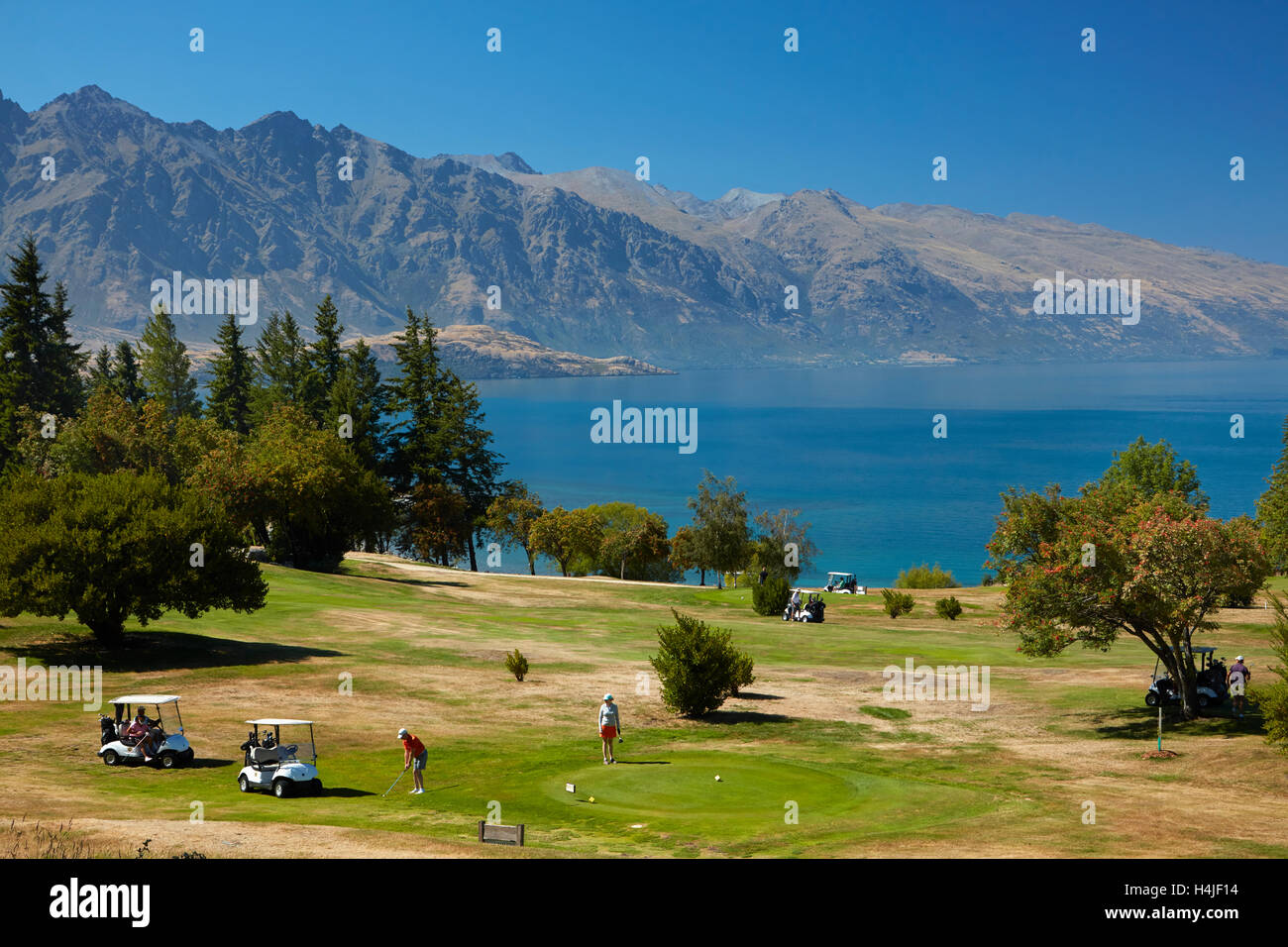 Golfer auf Kelvin Heights Golf Course, Lake Wakatipu und die Remarkables, Queenstown, Südinsel, Neuseeland Stockfoto