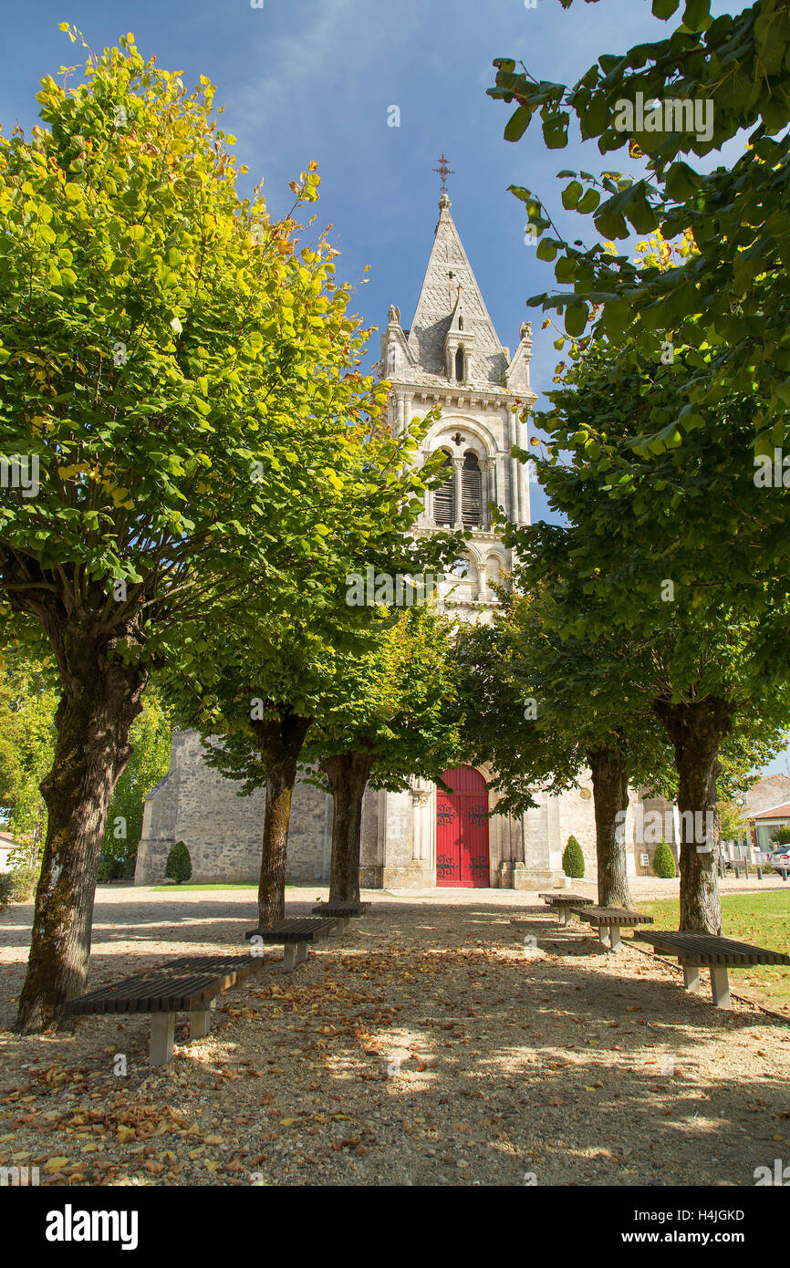 Allee der Bäume zu französische Kirche mit roten Tür und spire Stockfoto