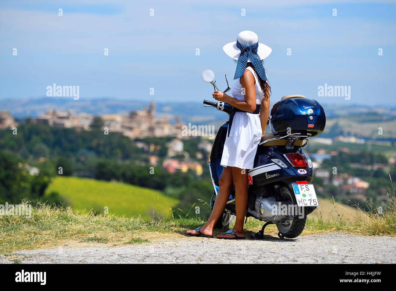 Frau mit weißen Sonnenhut neben Vespa Primavera Roller, Corinaldo, Marche, Italien Stockfoto