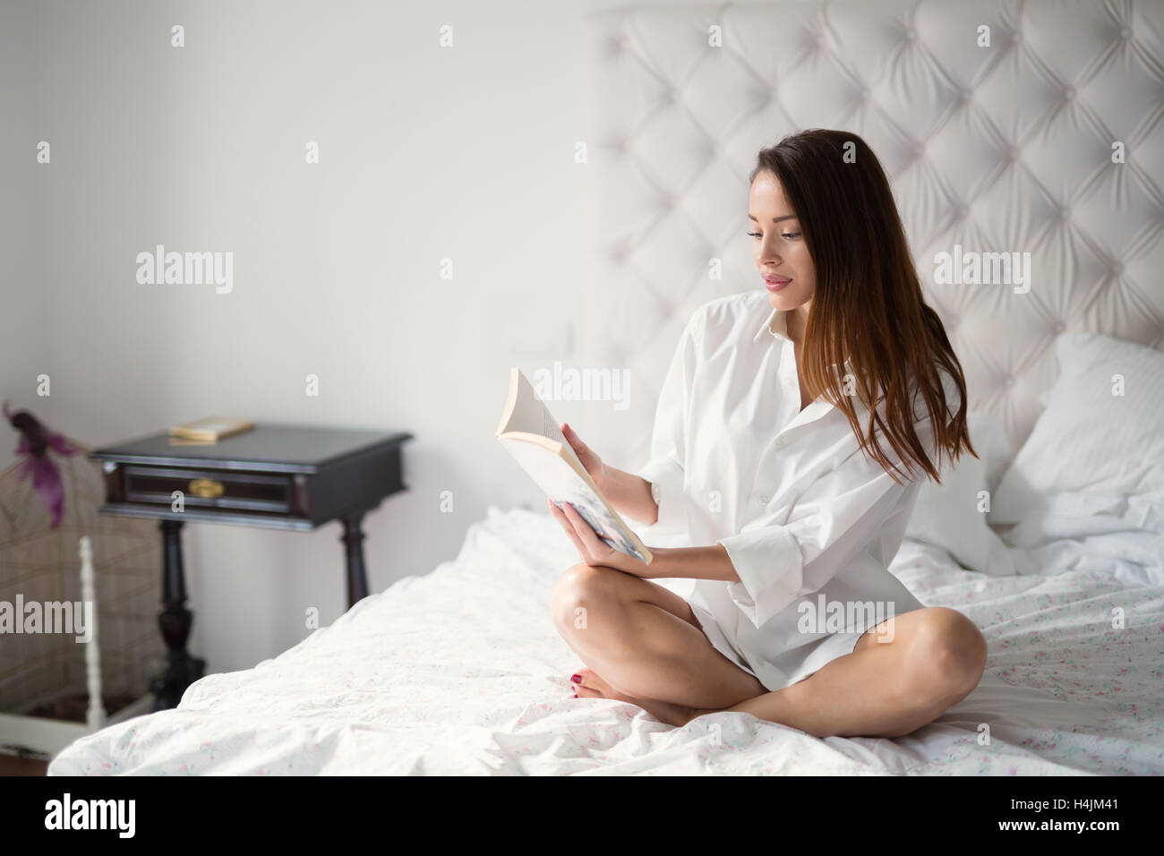 Schöne Frau Buch beim liegen im Bett Stockfoto