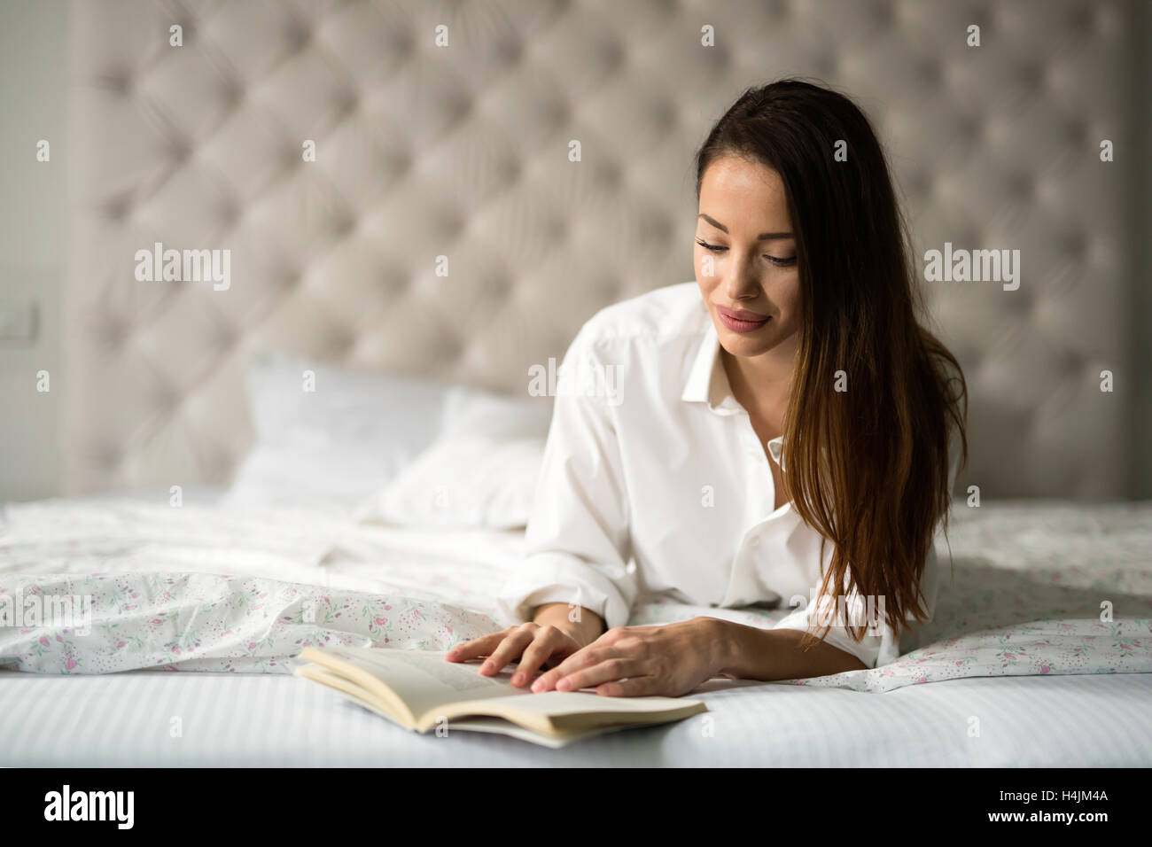 Schöne Frau Buch beim liegen im Bett Stockfoto