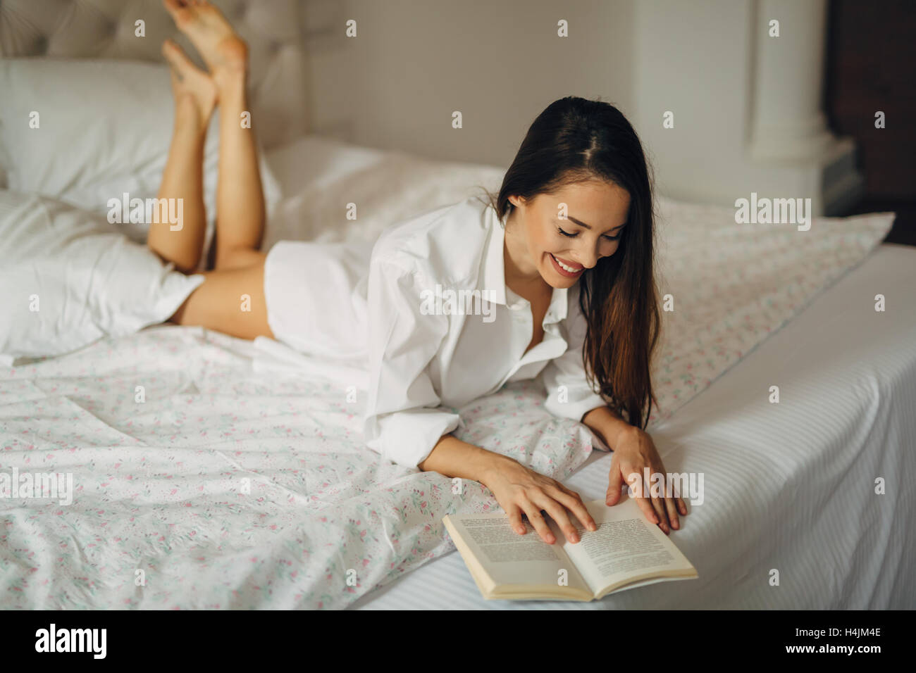 Schöne Frau Buch beim liegen im Bett Stockfoto