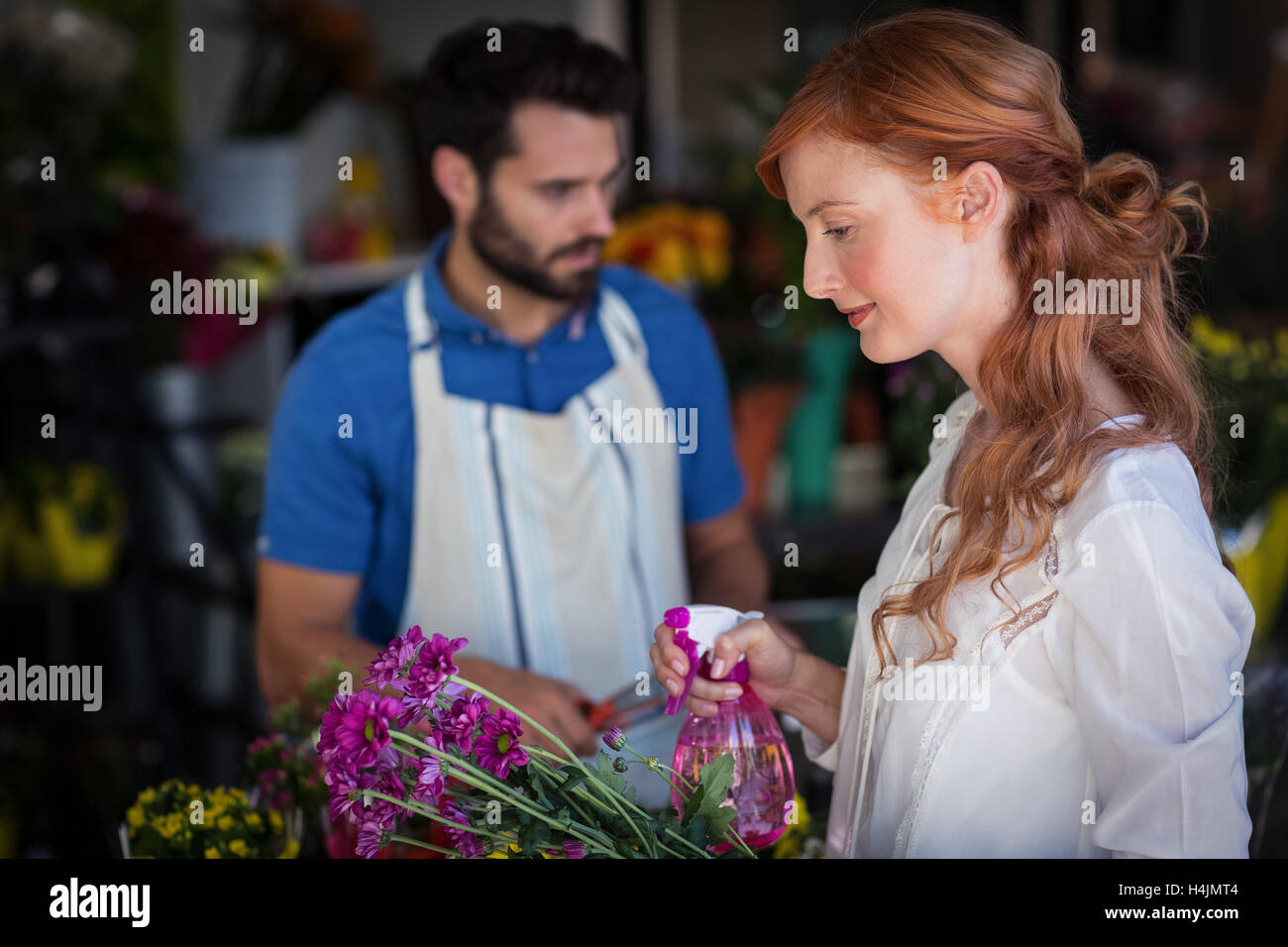 Aufsprühen von Wasser auf Blumenstrauß während Vorbereitung Blumenstrauß Mann Frau Stockfoto