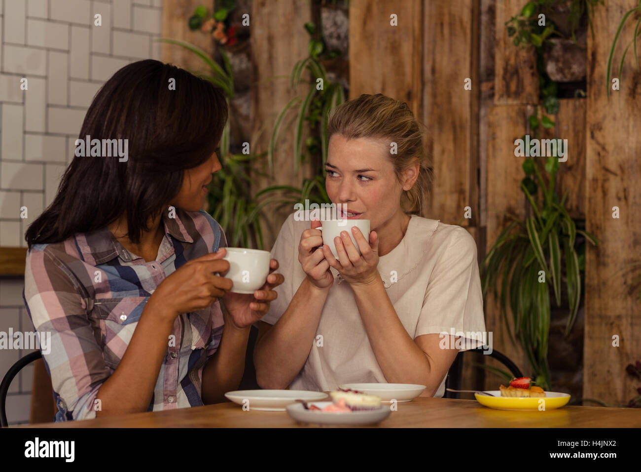 Freundinnen miteinander interagieren, während mit Kaffee Stockfoto