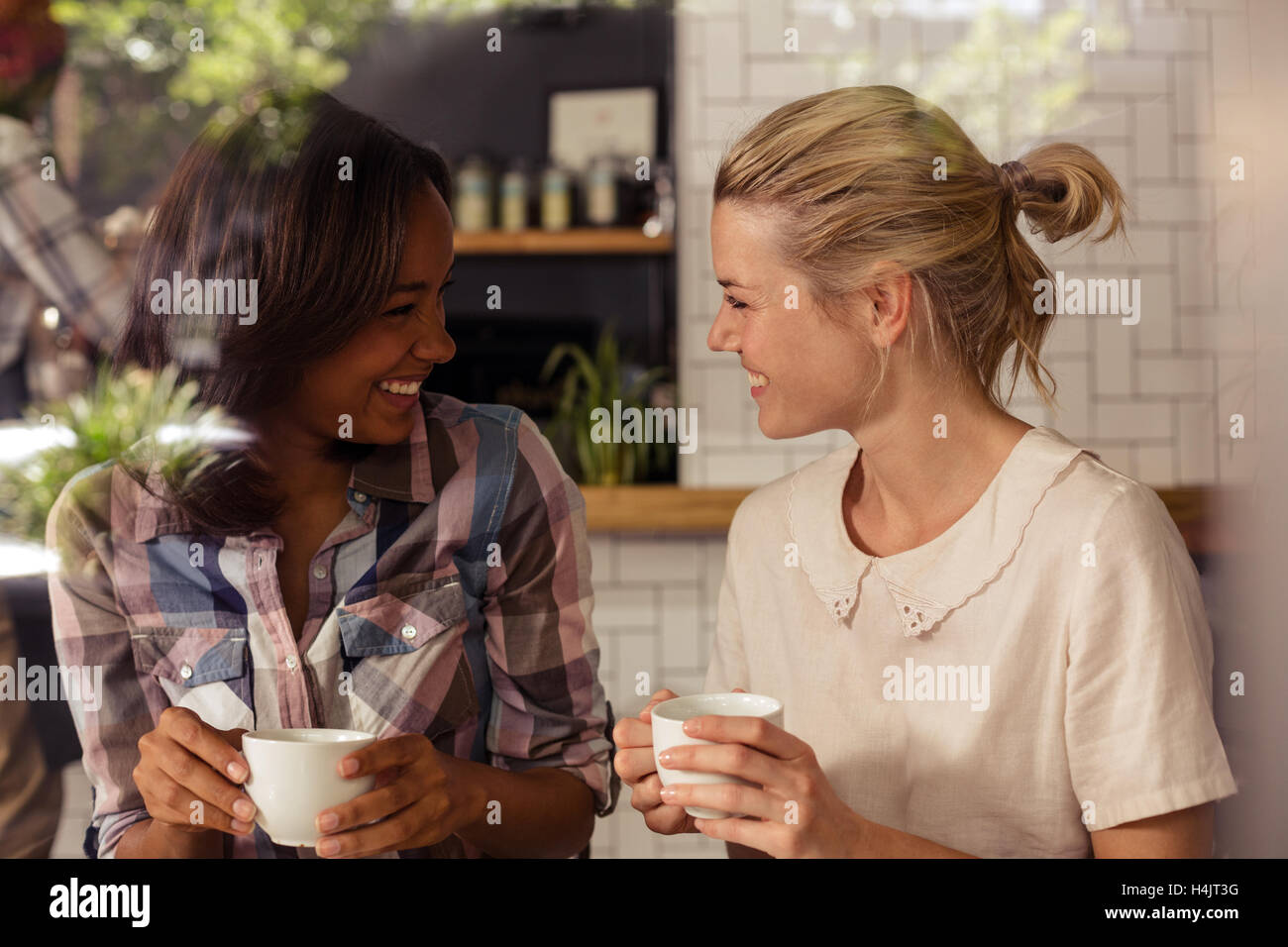 Freundinnen miteinander interagieren, während mit Kaffee Stockfoto