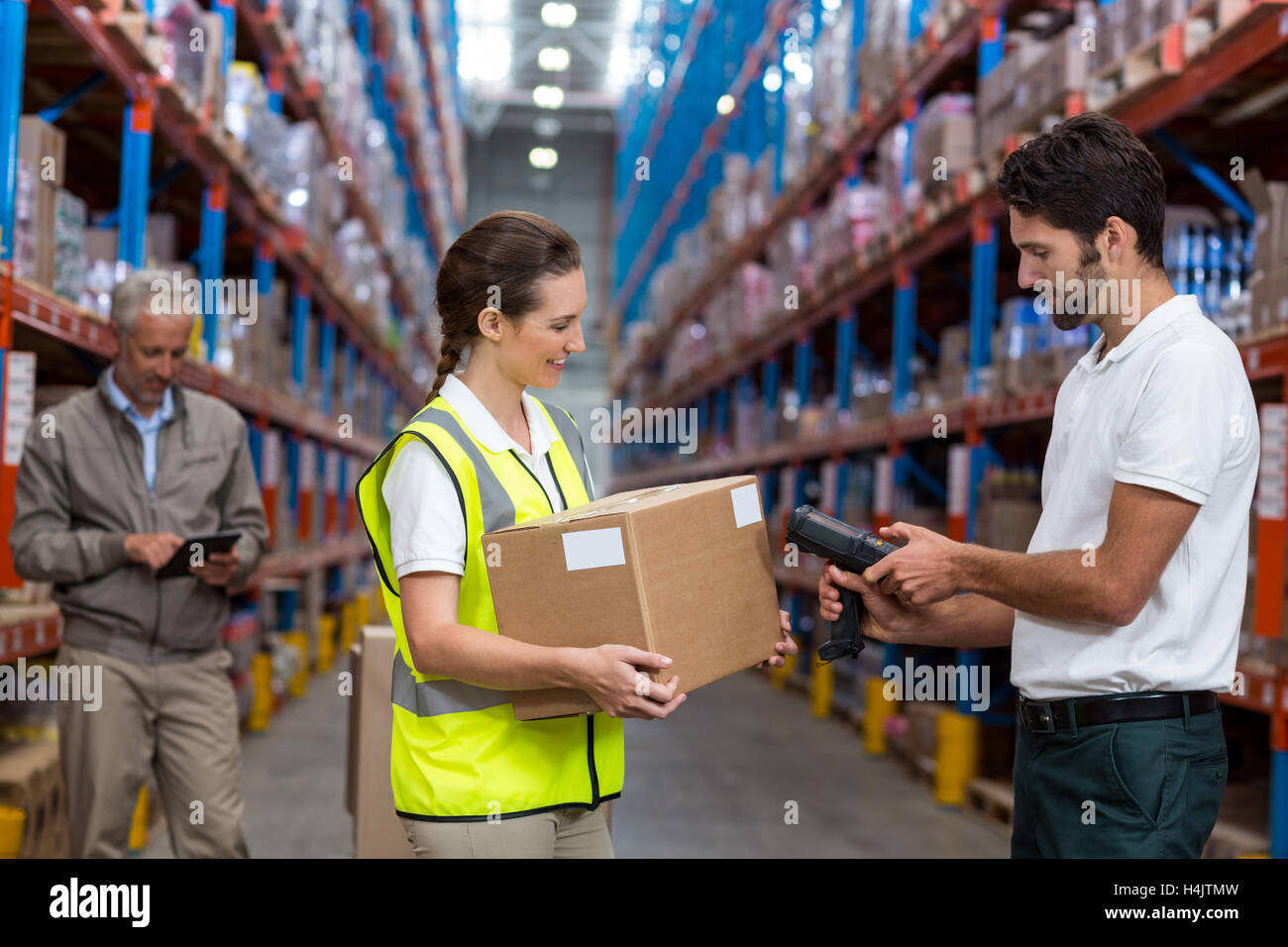 Arbeitnehmerin holding Karton beim männlichen Arbeitnehmer Barcode Scannen Stockfoto