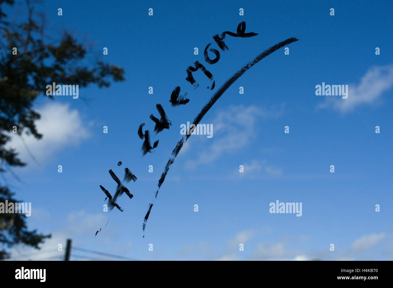 Hallo alle gekritzelt in schwarzem Filzstift auf einem Fenster mit blauem Himmel, Bäume und kleine Wolken im Hintergrund Stockfoto