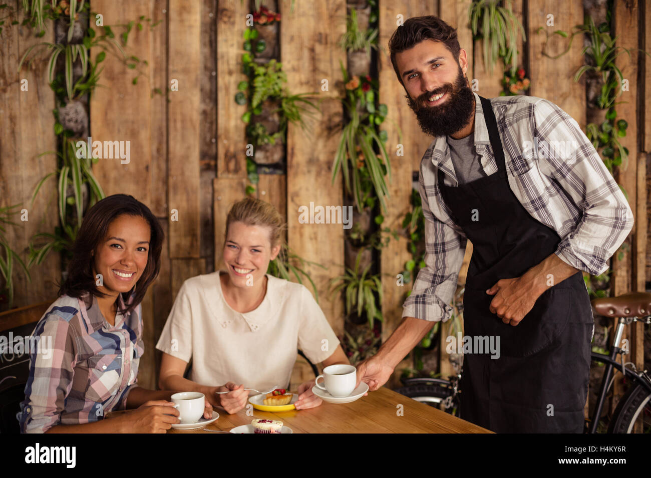 Kellner mit einer Tasse Kaffee an Kunden Stockfoto