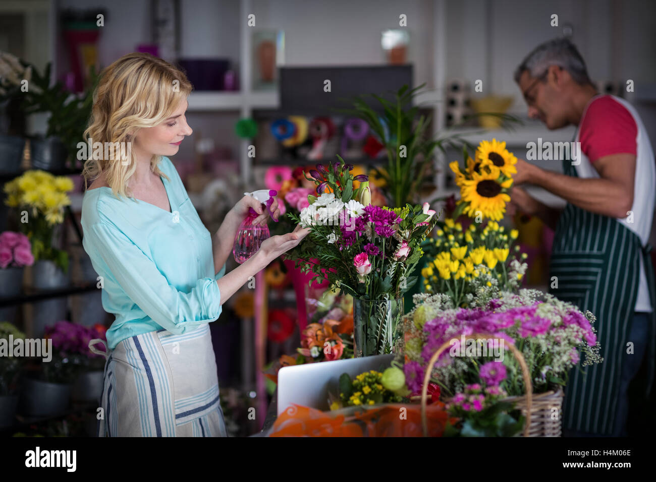 Floristen Sprühwasser auf Blumen im Blumenladen Stockfoto