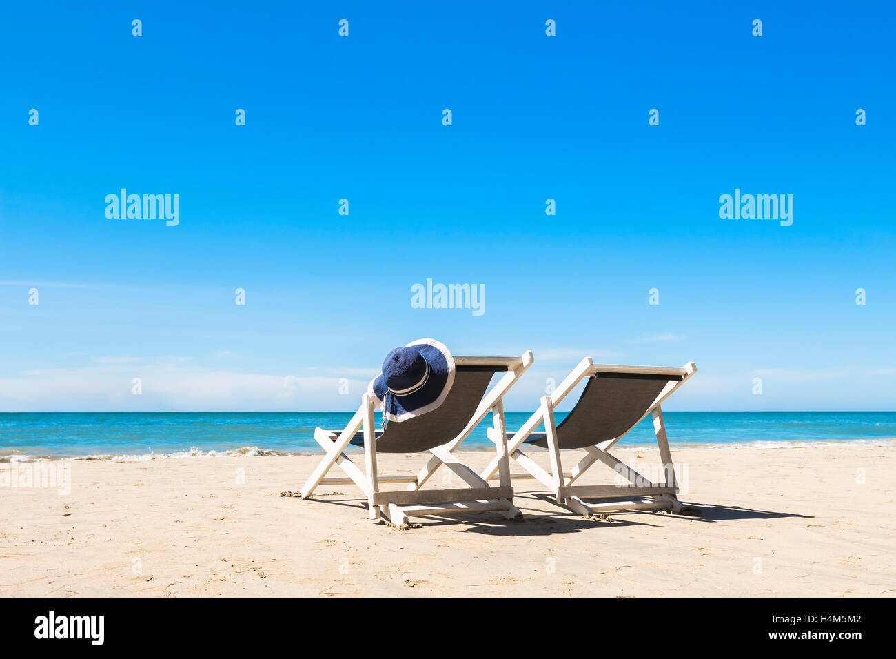 Zwei weiße Liegestühle und einen Hut zum Entspannen am Strand, sonnigen Tag Stockfoto