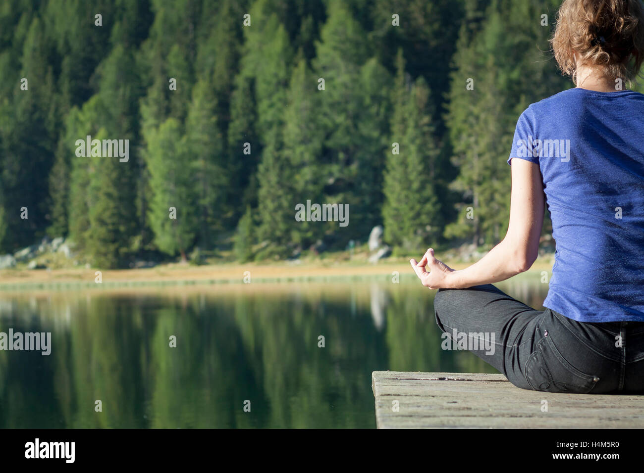 Hübsche Frau praktizieren Yoga am See Stockfoto