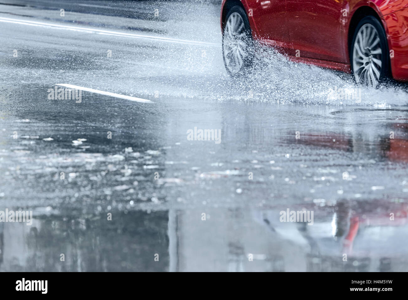 rotes Auto fahren durch Wasser Pfütze mit Wasser spritzt aus den Rädern Stockfoto