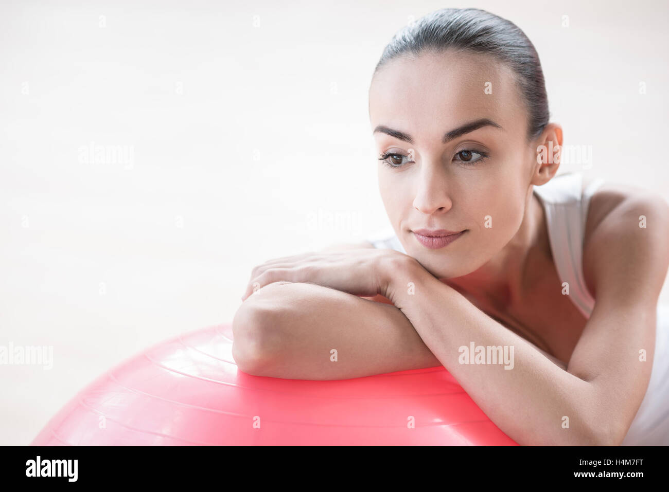 Ernste nachdenkliche Frau stützte sich auf ein rosa Fitnessball Stockfoto